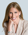 Elizabeth Baron in a beige blazer smiling with a blurred background