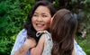 A wide angle of Esther and her daughter hugging and smiling outdoors